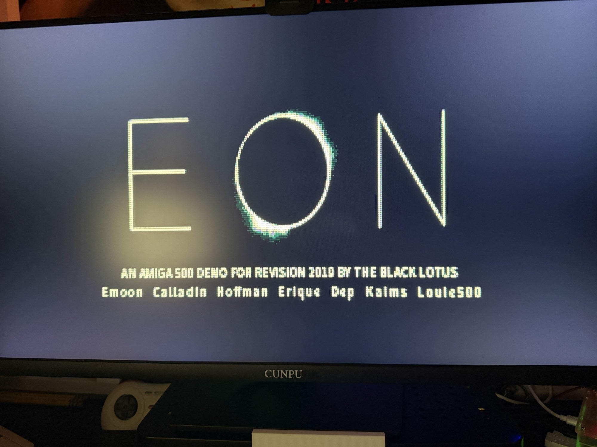 Title screen of the Amiga demo Eon by The Black Lotus, Revision 2019, with h0ffman in the credit line, on a CRT.
