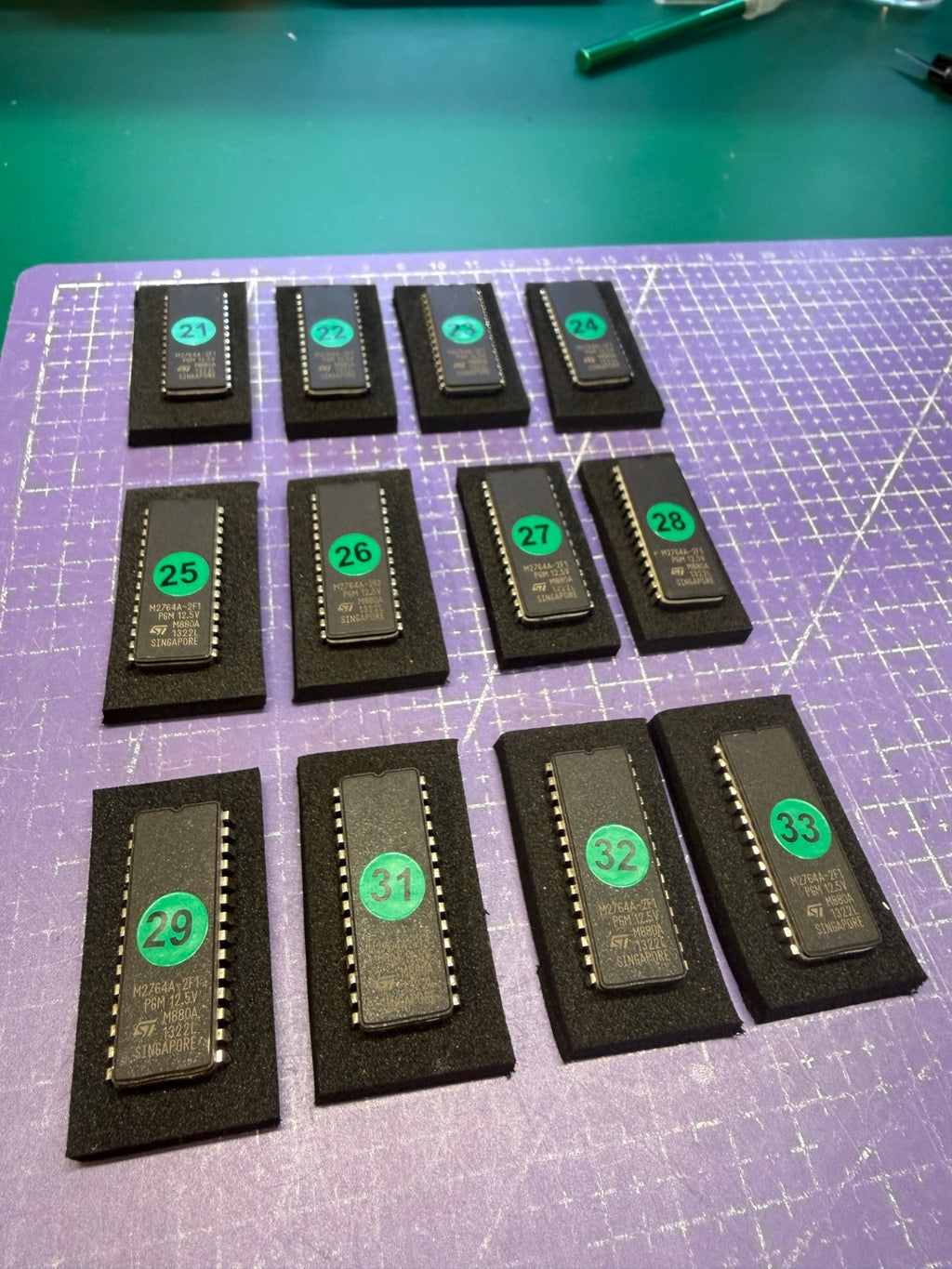 M2764A EPROMs programmed with marcelv's Grafik ROM II dump, each labeled with a green-dot tracking number, staged on antistatic foam ready for printer self-test before shipping